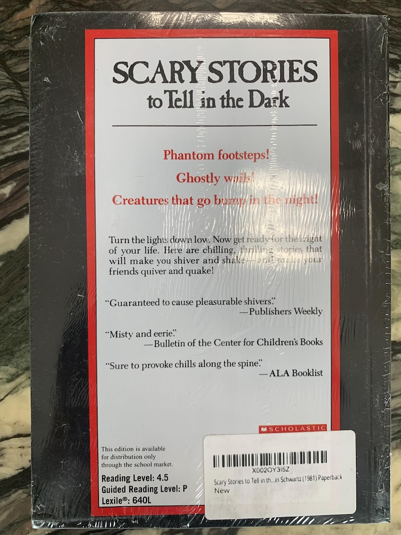 Puede incluir: Un libro de bolsillo titulado "SCARY STORIES to Tell in the Dark" con una cubierta negra y texto rojo y blanco. La contraportada presenta citas y una descripci&oacute;n que promete historias escalofriantes. El libro est&aacute; sellado en pl&aacute;stico.