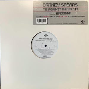 Puede incluir: Un álbum de vinilo blanco con Britney Spears y Madonna. El álbum se titula "Me Against The Music" e incluye el texto "Look for Britney's new album in the zone in stores November 18."
