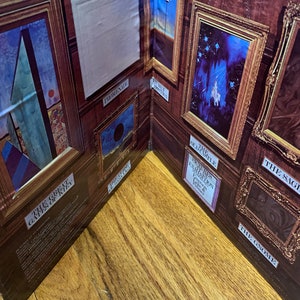 Pu&ograve; includere: Un diorama raffigurante una galleria con opere d'arte incorniciate. Le pareti della galleria sono marroni con dipinti con cornice dorata. Le opere d'arte includono un faro, un castello e un cerchio nero. Il testo include "Promenade" e "The Gnome".