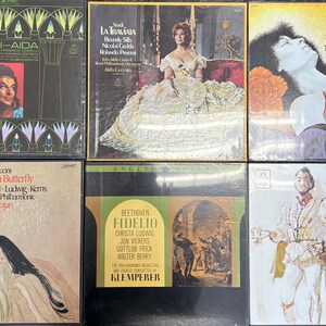 May include: A collection of six vintage vinyl record albums. The album covers feature opera titles like "Verdi-Aida," "La Traviata," and "Carmen." The covers display images of performers and artwork, with text including the composer and performer names.
