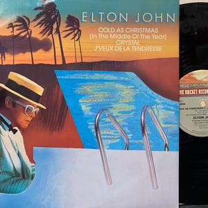 Vinilo vintage - Elton John, Cold as Christmas (en mitad de año), Crystal, J’Veux de la Tendresse, UK Rocket Records, 45 RPM, Sencillo