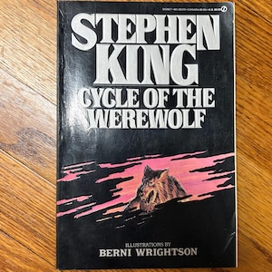 May include: A paperback book titled "Stephen King Cycle of the Werewolf" with a black cover. The title is in white, bold letters. The cover art features a werewolf illustration in front of pink and black streaks.