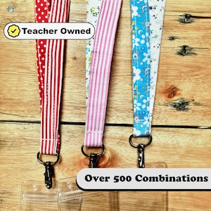 May include: Three colorful fabric lanyards with black metal clasps and clear plastic badge holders. The lanyards have a red and white polka dot pattern, a pink and white striped pattern, and a blue and white floral pattern. The text "Teacher Owned" is visible in the image. The text "Over 500 Combinations" is also visible in the image.