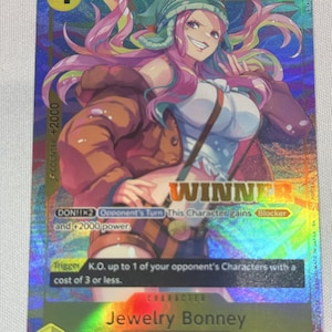 May include: A holographic One Piece trading card featuring the character Jewelry Bonney with pink hair, a green beanie, and a brown jacket. The card displays the text WINNER, 4000 power, and game mechanics including DON!!x2 and a K.O. trigger effect.