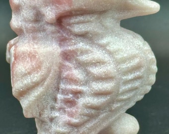 May include: A pink and white seahorse figurine carved from stone. The figurine is detailed with textured scales and a small eye.
