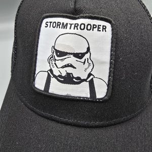 May include: Black trucker hat with a white patch featuring a Stormtrooper from Star Wars. The patch has the text "STORMTROOPER" above the image.