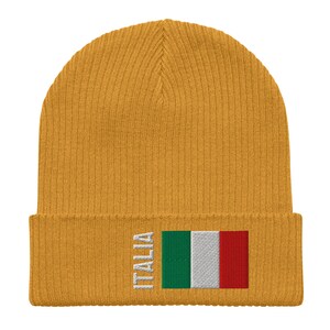 May include: A mustard yellow knit beanie with a white embroidered Italian flag and the word "ITALIA" on the front.