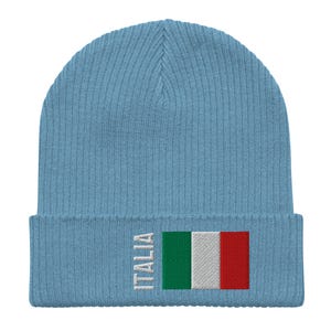 May include: A light blue knitted beanie with the word "ITALIA" and the Italian flag embroidered on the front.