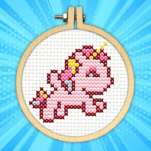 May include: A pink and white cross-stitch embroidery of a unicorn with a yellow horn and mane, framed in a wooden hoop.