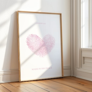 May include: A framed print featuring a pink fingerprint heart design and the text "Genesis 1:27 Made in His Image".