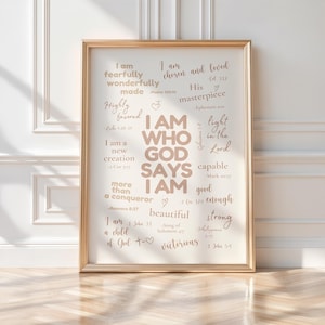May include: A framed print with the words "I AM WHO GOD SAYS I AM" in a beige font. The print includes inspirational phrases like "fearfully wonderfully made" and "chosen and loved". The frame is gold.