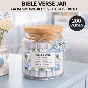 May include: A glass jar with a wooden lid and twine bow, filled with small paper verses. The jar has a floral label that says "Read me when you are feeling..." and a heart-shaped tag with a name. The text "BIBLE VERSE JAR" is at the top.