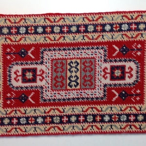 May include: A small, red, white, and blue patterned rug with a traditional design. The rug has a geometric pattern with a central medallion.
