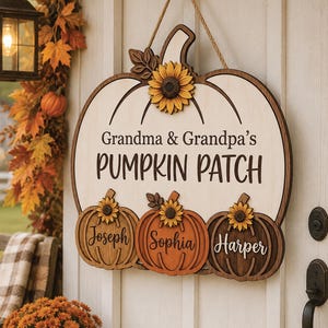 Pode incluir: Uma placa de porta de madeira em forma de abóbora com o texto "Grandma & Grandpa's PUMPKIN PATCH" e três abóboras menores abaixo com os nomes "Joseph", "Sophia" e "Harper". A placa é decorada com girassóis e pendurada por uma corda.