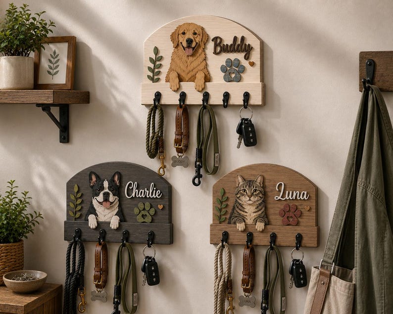 K&ouml;nnte beinhalten: Drei wandmontierte Leinen- und Schl&uuml;sselhalter aus Holz mit geschnitzten Tierfiguren. Das obere Brett zeigt einen Golden Retriever namens Buddy, w&auml;hrend die unteren Bretter einen Boston Terrier namens Charlie und eine getigerte Katze namens Luna zeigen.