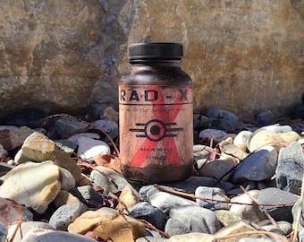 May include: A dark brown plastic bottle with a black screw-top lid, featuring a label that reads RAD-X, for use in high radiation areas, made in the U.S.A., 50 tablets, and a central circular graphic with horizontal lines on a weathered background.