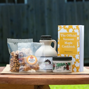 May include: A table setting with maple syrup, maple candy, maple nuts, and a cookbook titled "The Official Vermont Maple Cookbook, Third Edition".