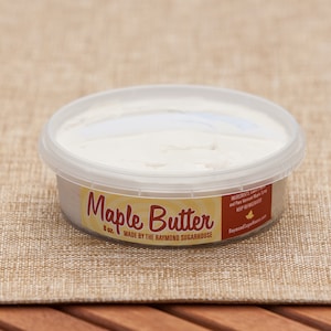 May include: A clear plastic container of maple butter, labeled "Maple Butter 8 oz. Made by the Raymond Sugarhouse".