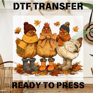 May include: DTF TRANSFER and READY TO PRESS text above and below a graphic of three chickens wearing fall attire. The chickens are wearing hats, scarves, and boots, standing on a bed of autumn leaves. The chickens are brown, orange, and white.