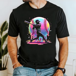 May include: Black t-shirt featuring a vibrant graphic of a baseball player swinging a bat. The design includes a colorful baseball with dripping paint effect. The player is in silhouette, adding a dynamic feel to the sports-themed apparel.