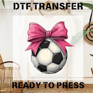 May include: A white t-shirt with a pink bow and a soccer ball design. The text "READY TO PRESS" is printed below the design.