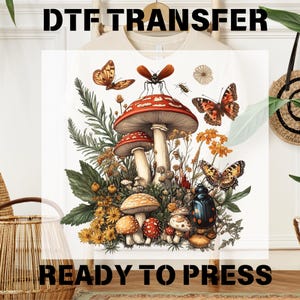 May include: A white t-shirt with a colorful illustration of mushrooms, butterflies, and insects. The design features red and white mushrooms, yellow and orange flowers, and a variety of insects. The text "DTF TRANSFER READY TO PRESS" is printed on the bottom of the shirt.