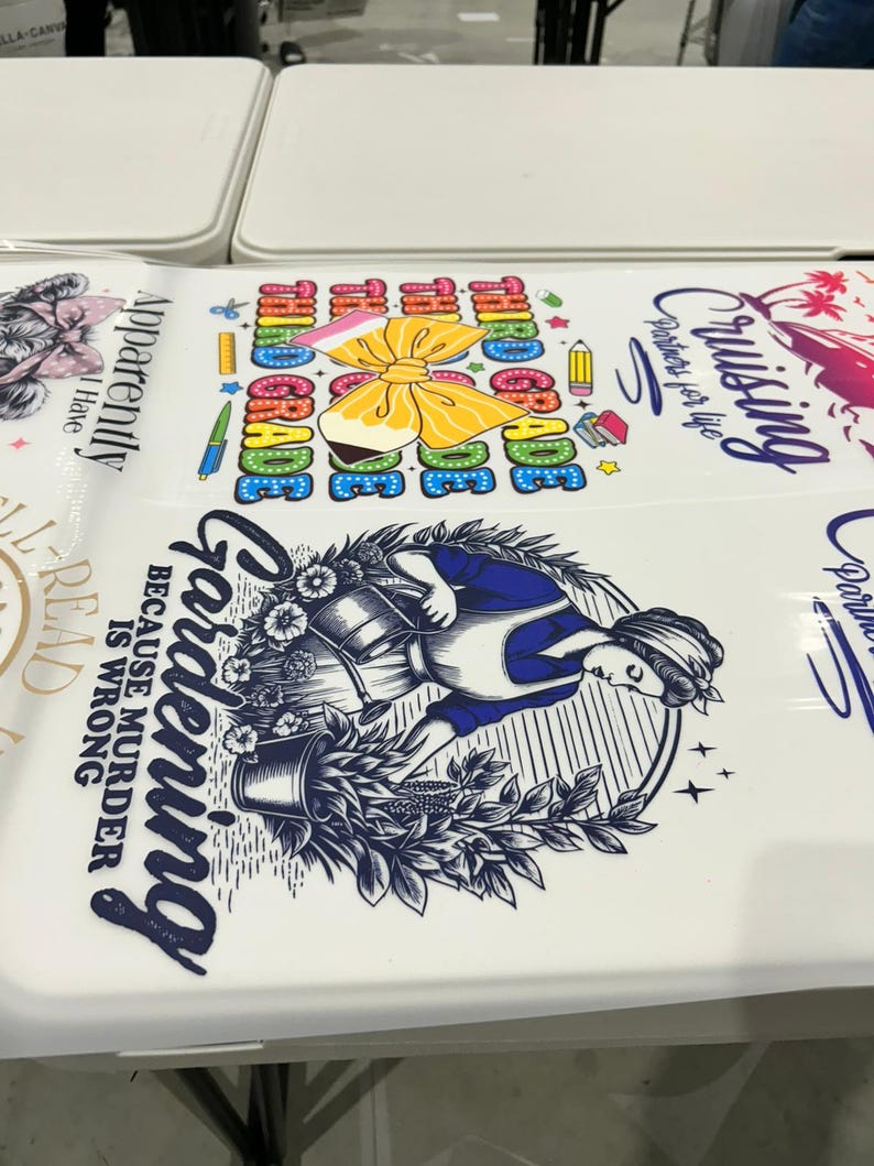 May include: White surface with various graphic designs. One design features a woman gardening with the text "Gardening because murder is wrong." Another design says "Third Grade" with a bow and pencils.