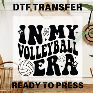 May include: Black and white graphic design with the text "In My Volleyball Era" in a retro font. The design includes a volleyball, a peace sign, a lightning bolt, and a smiley face. The text "Ready To Press" is below the design.