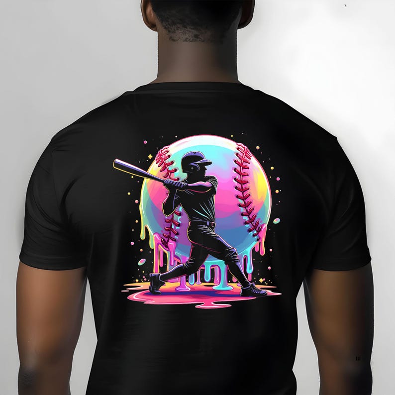 May include: Black t-shirt featuring a baseball player silhouette in action, swinging a bat. A large, colorful baseball with dripping paint effect is behind the player. The design incorporates vibrant hues of pink, blue, and yellow.