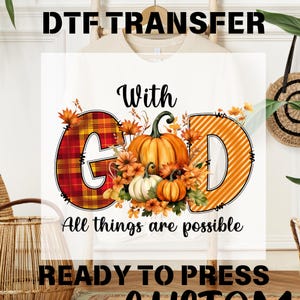 May include: White t-shirt with a DTF transfer design. The design features the words "With God" and "All things are possible." The design includes a plaid "G" and an orange striped "D" with pumpkins and autumn leaves.