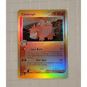 May include: A holographic Camerupt Pokémon trading card. The card features a reddish-orange creature with a gray back and three orange circles on its side. The card has the text "Camerupt" and "90 HP".