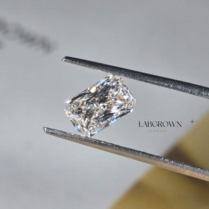 May include: A clear, rectangular, lab-grown diamond held in tweezers. The diamond is cut into a square shape with rounded edges. The tweezers are labeled "Labgrown Diamonds".