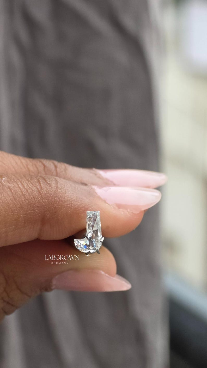 Puede incluir: Un pendiente de diamante cultivado en laboratorio con corte rectangular y base curva. El pendiente es transparente y brillante, con el texto "LABGROWN GERMANY" visible.