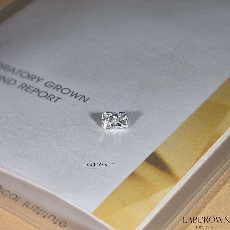 May include: A clear rectangular lab-grown diamond on a white card with the text "Laboratory Grown Diamond Report" and "Labgrown Germany".