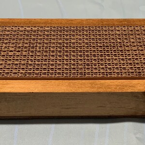 May include: A wooden box with a corrugated cardboard insert. The box is a light brown color and the insert is a darker brown color.