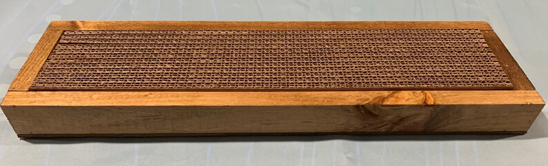 May include: A wooden box with a corrugated cardboard insert. The box is a light brown color and the insert is a darker brown color.