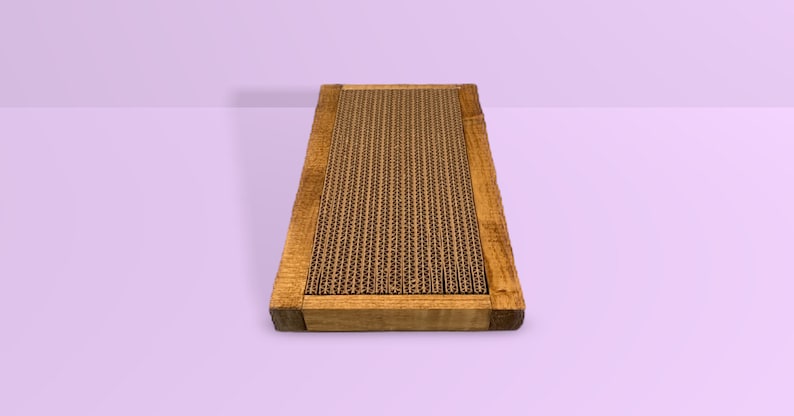 May include: A rectangular scratching post for cats with a brown cardboard scratching surface framed in natural wood.