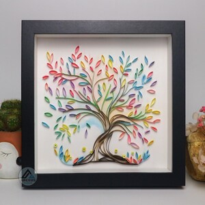 May include: A framed paper art piece featuring a colorful tree with a rainbow of leaves. The tree is made of paper and is framed in a black frame.