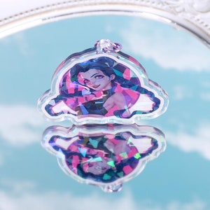 May include: A holographic charm featuring a cartoon character with purple hair and a pink and blue background.