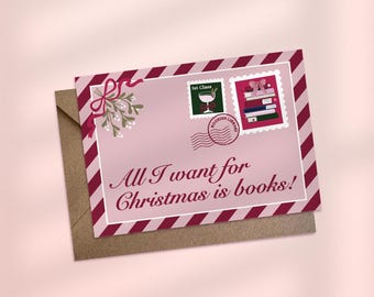 May include: A pink greeting card with a brown envelope. The card features a red and white striped border, mistletoe, and postage stamps. Text on the card reads "All I want for Christmas is books!"