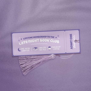 Może przedstawiać: Fioletowy zakładka z frędzlem, z tekstem "Late Night Book Club" i ikonami przedstawiającymi półksiężyc, stos książek i filiżankę kawy. Zakładka zawiera również napis "Lifetime Membership to the Late Night Book Club" i "Admit One Bookworm".