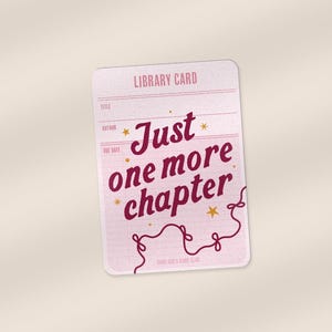 May include: A light pink library card with the text "Just one more chapter" in a burgundy script. The card has a vintage aesthetic with lines for information and decorative stars.