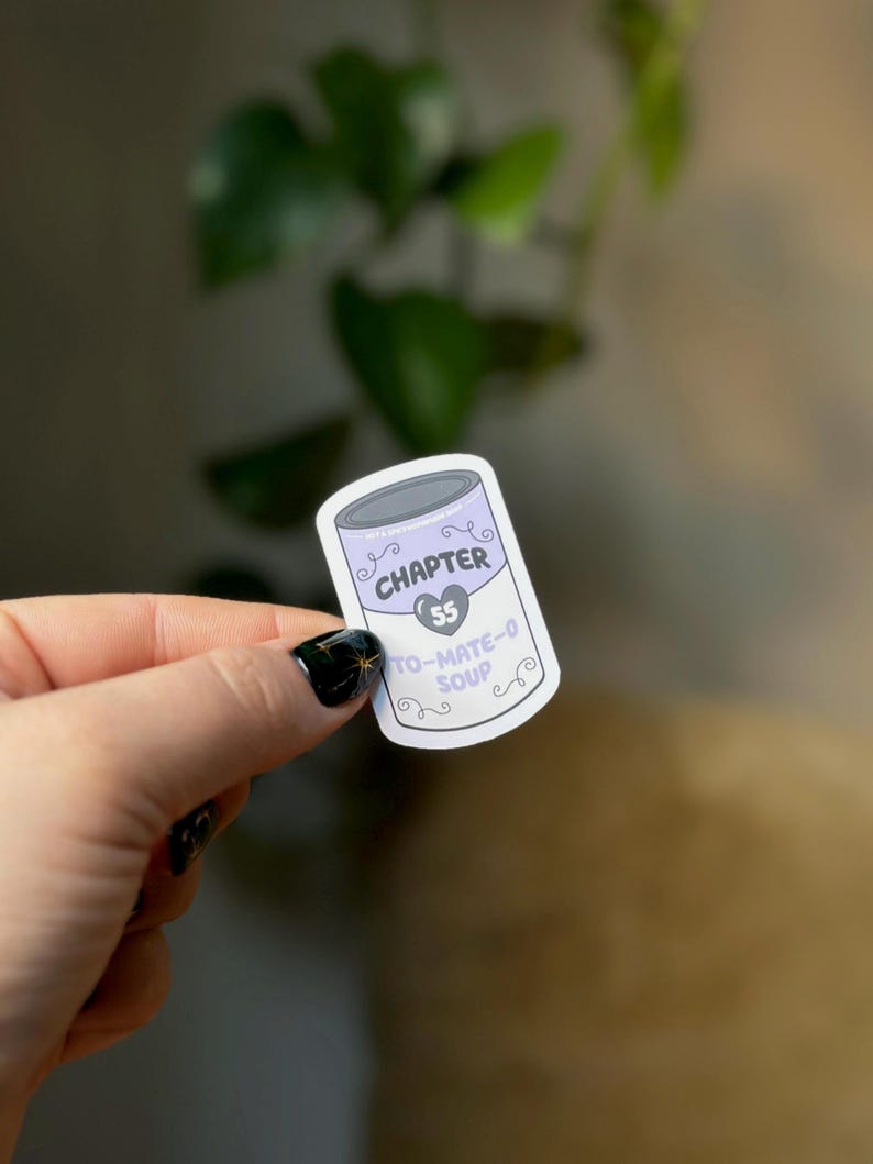 May include: A white sticker with a purple can design. The can has the text "CHAPTER 55" and "TO-MATE-O SOUP" on it.