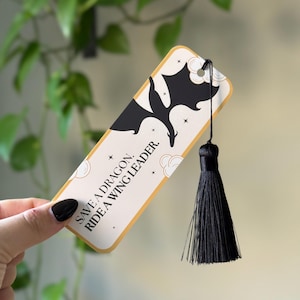 May include: A black and gold bookmark with a black silhouette of a dragon and the text "Save a dragon. Ride a wing leader."