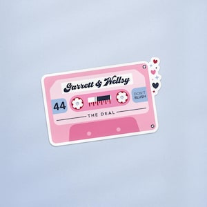 May include: A pink cassette tape sticker with the text "Garrett & Wellsy" and "The Deal." The sticker also features the number "44" and the words "Don't Blush." Decorative hearts and stars are on the right side.