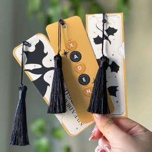 May include: Three yellow bookmarks with black tassels and a black silhouette of a dragon. The bookmarks have the text "Save the Dragon" and the letters "X, A, D, E, N" on them.