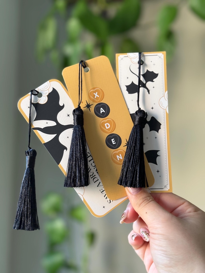 May include: Three yellow bookmarks with black tassels and a black silhouette of a dragon. The bookmarks have the text "Save the Dragon" and the letters "X, A, D, E, N" on them.