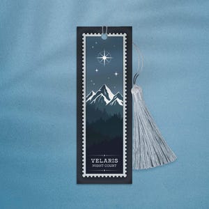 May include: A black bookmark with a silver border and a silver tassel. The bookmark features a blue and white illustration of a mountain range with a star and the text "VELARIS NIGHT COURT".