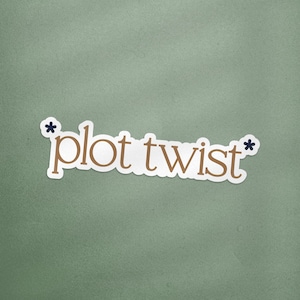May include: A white sticker featuring the phrase "plot twist" in a brown serif font, with navy blue asterisks. The sticker is set against a muted green backdrop.