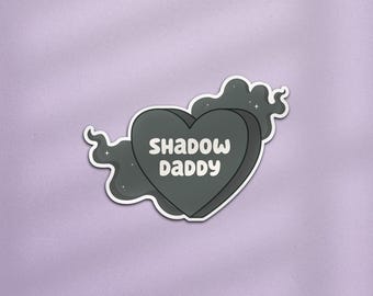 Op de afbeelding: Een zwarte sticker in de vorm van een hart met de tekst "Shadow Daddy" in witte letters. De sticker is omgeven door een zwarte wolk met witte sterren.